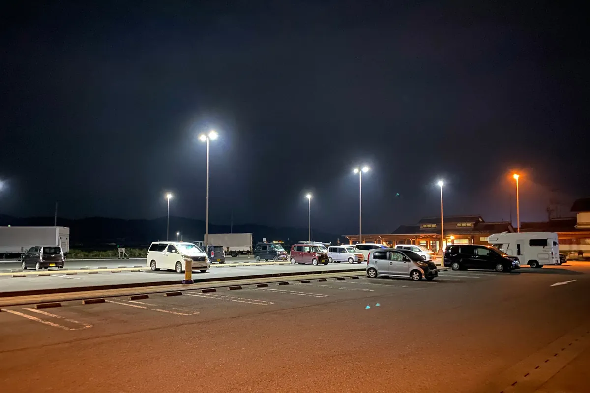 Roadside station parking at dusk with cars and vans